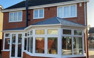 Replacement conservatory frames with white uPVC windows installed on brick house in Cheshire